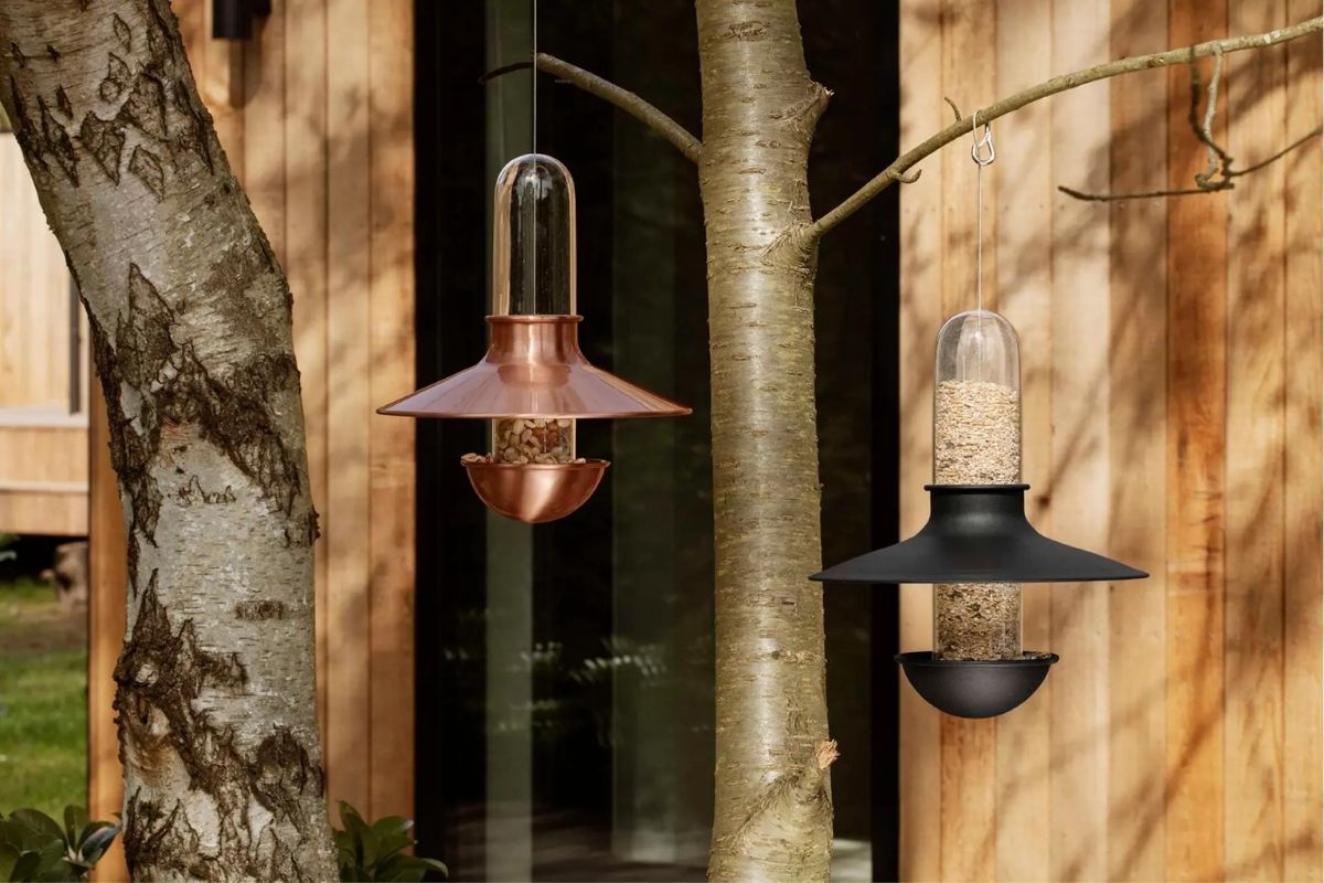 Eva Solo De Luxe copper and black bird feeders filled with bird food and hanging in a tree ready for hungry NZ native birds.